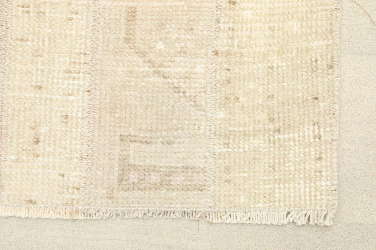 Close-up of the rug's short fringe and low pile, showing beige and tan geometric patterns