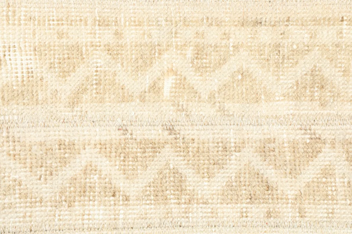 Close-up of the hand-knotted wool pile and the distinct tan geometric motifs.