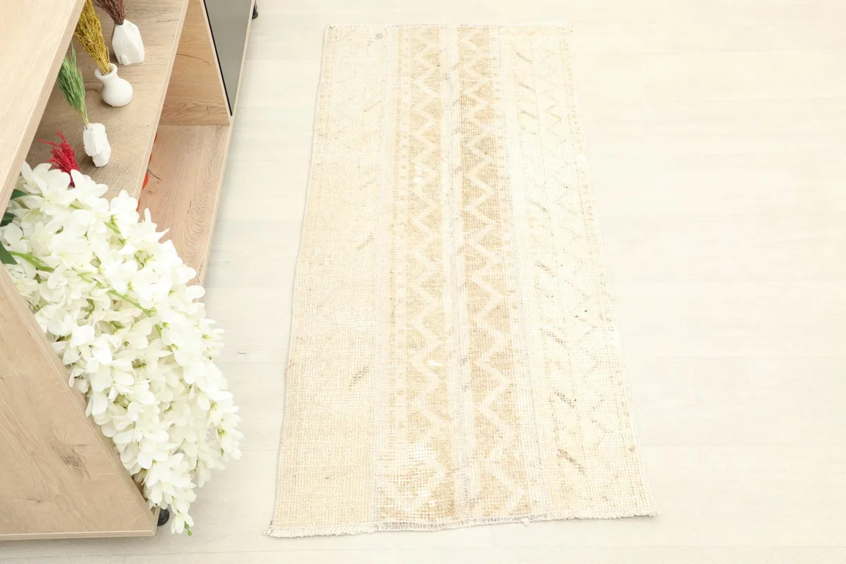 Overhead view of the hand-knotted beige and tan vintage rug, showing its full design.
