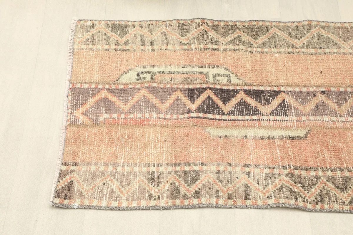 Angled view from one end of the rug, showing the blend of rose and darker geometric sections.