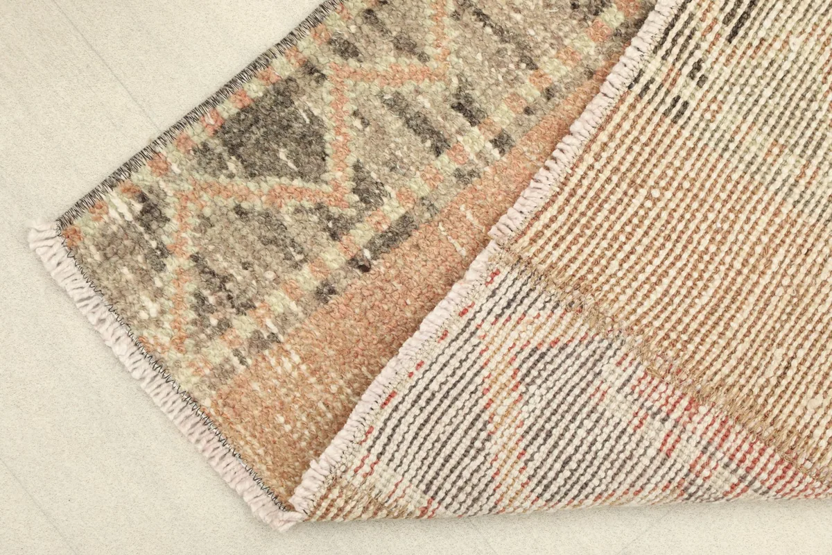 View of the rug's reverse side and a corner of the front, showing the hand-knotted construction.