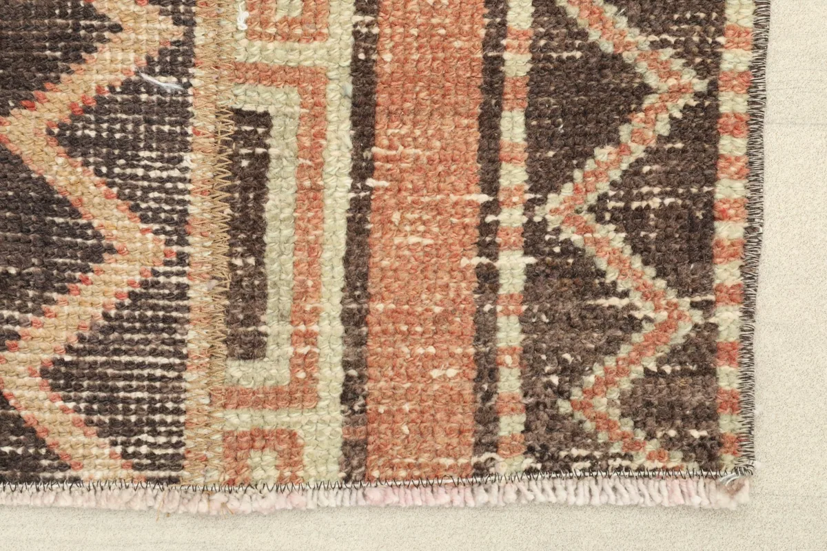 Close-up detail of the hand-knotted pile, showing the rust, brown, and beige colors and zigzag patterns.