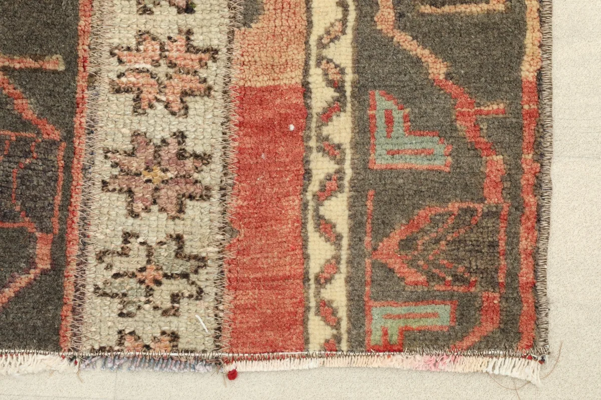 Close-up detail of the rug's fringe and a section of the charcoal, rust, and beige striped pattern.