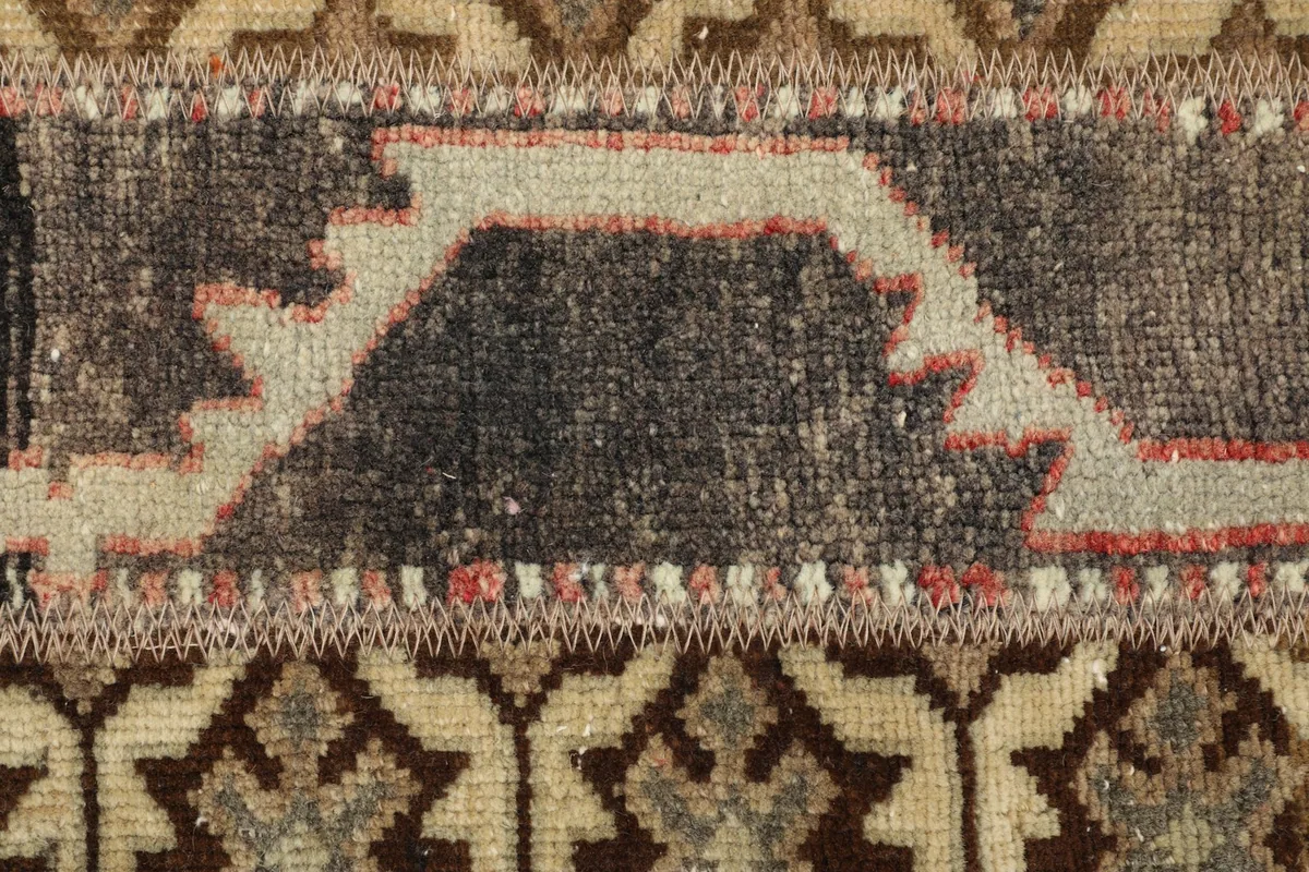 Detailed view of a charcoal and beige geometric section with hints of red stitching