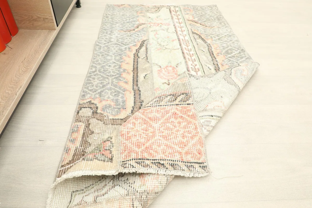 The vintage rug partially folded, showing its flexibility and the overall design from an angle.
