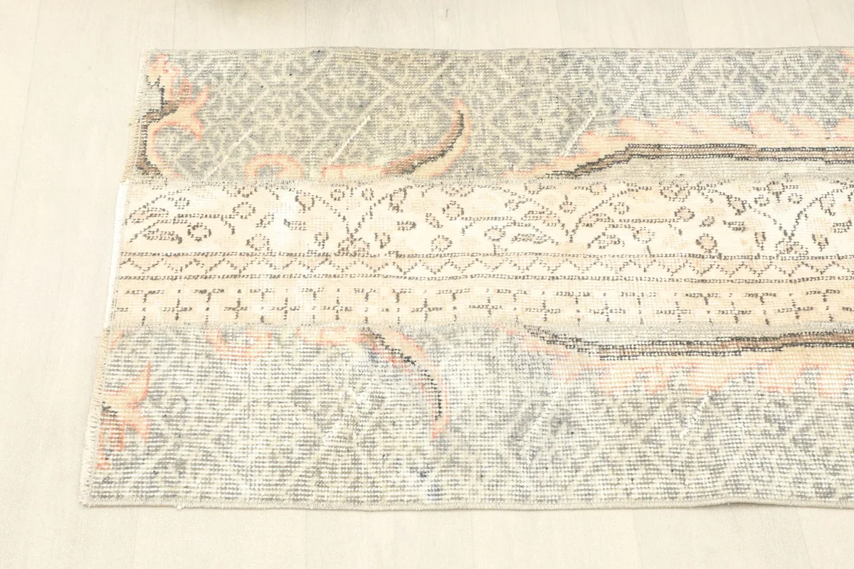 Side angle view of the rug, showing the transition between the gray field and ivory patterns.