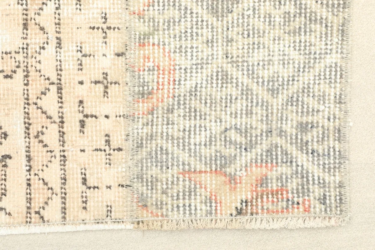 Close-up detail of the rug's geometric patterns and the blend of gray, ivory, and rust colors.