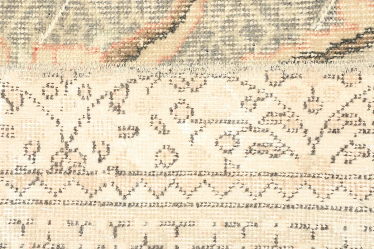 Detailed view of the intricate motifs within the ivory central panel of the vintage rug.