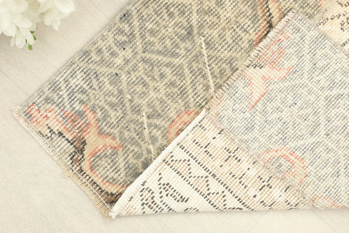 Folded corner of the rug, showing the wool pile texture and the cotton foundation.