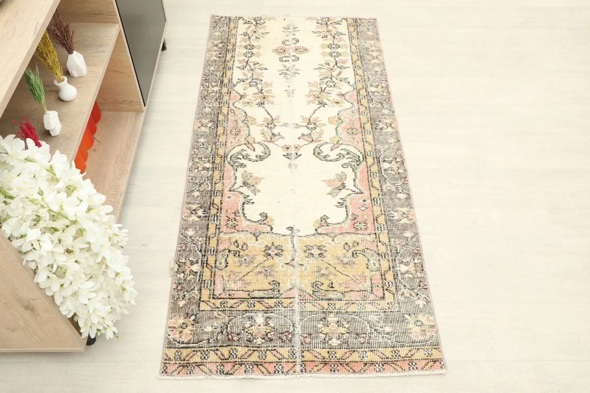 Overhead view of the vintage Anatolian runner, showing its central ivory field and floral motifs.