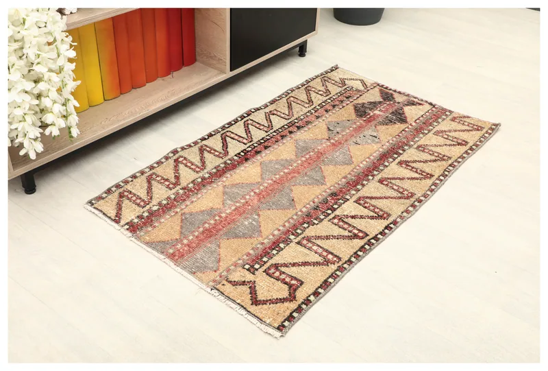 Full top view of the tan, red, and gray geometric vintage Anatolian area rug on a white background.