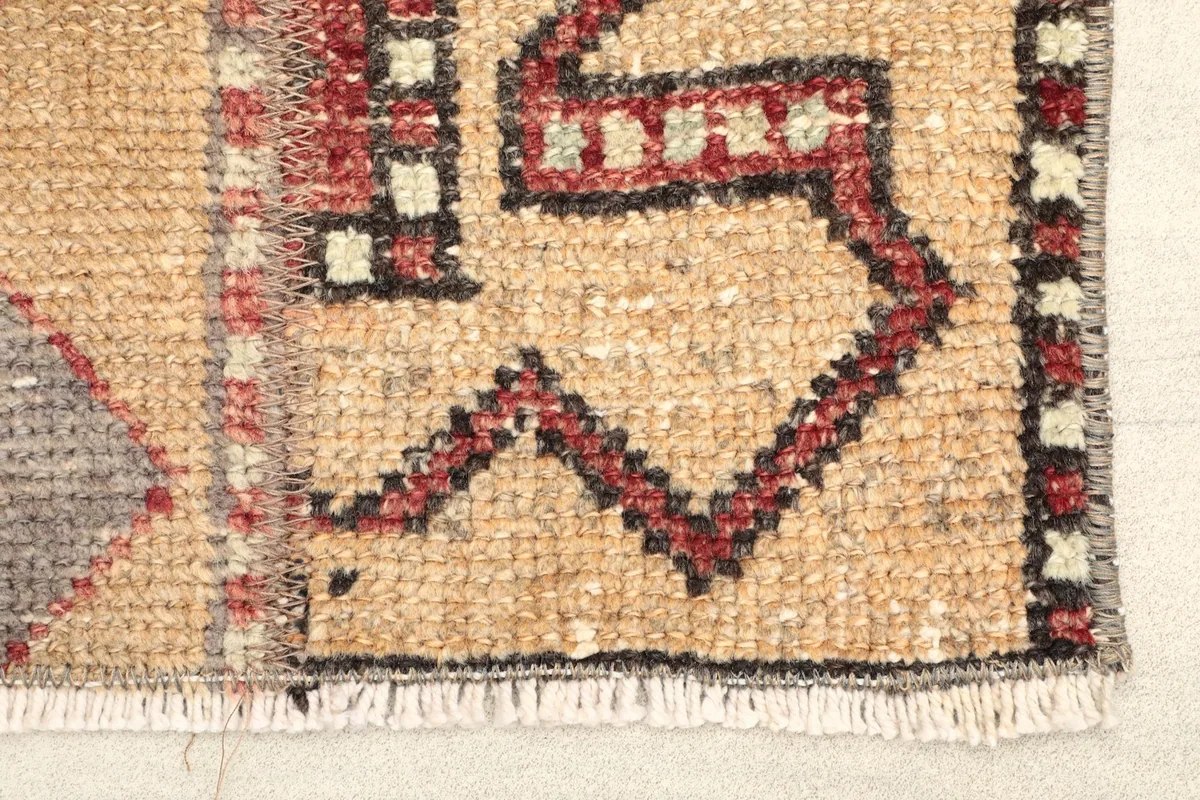 Close-up detail of the rug's border and fringe, highlighting the hand-knotted texture and red, black, and tan threads.