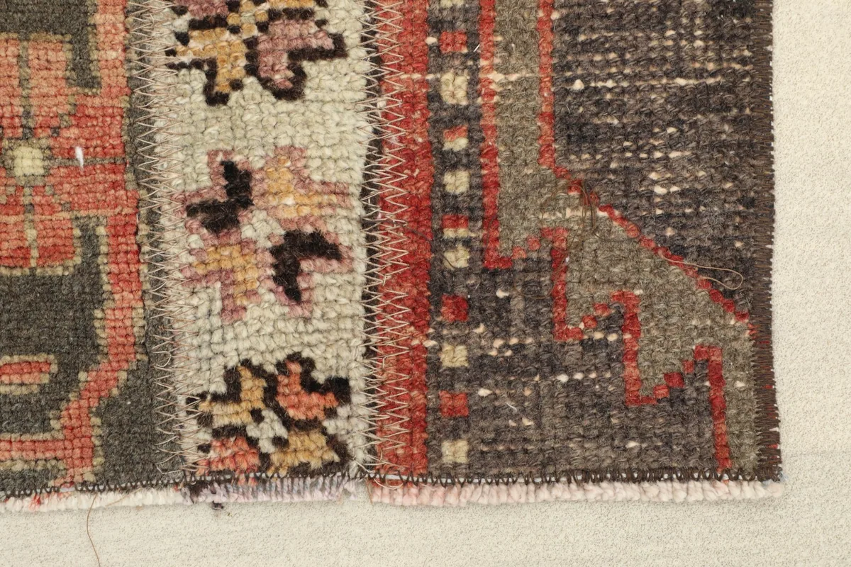 Close-up detail of the rug's stitching and varying textures between the charcoal and rust striped sections.