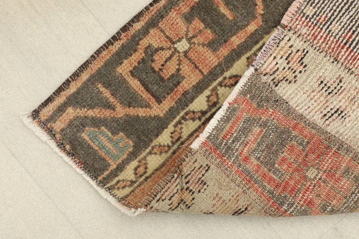 Corner of the rug folded back, revealing the reverse side and cotton foundation.
