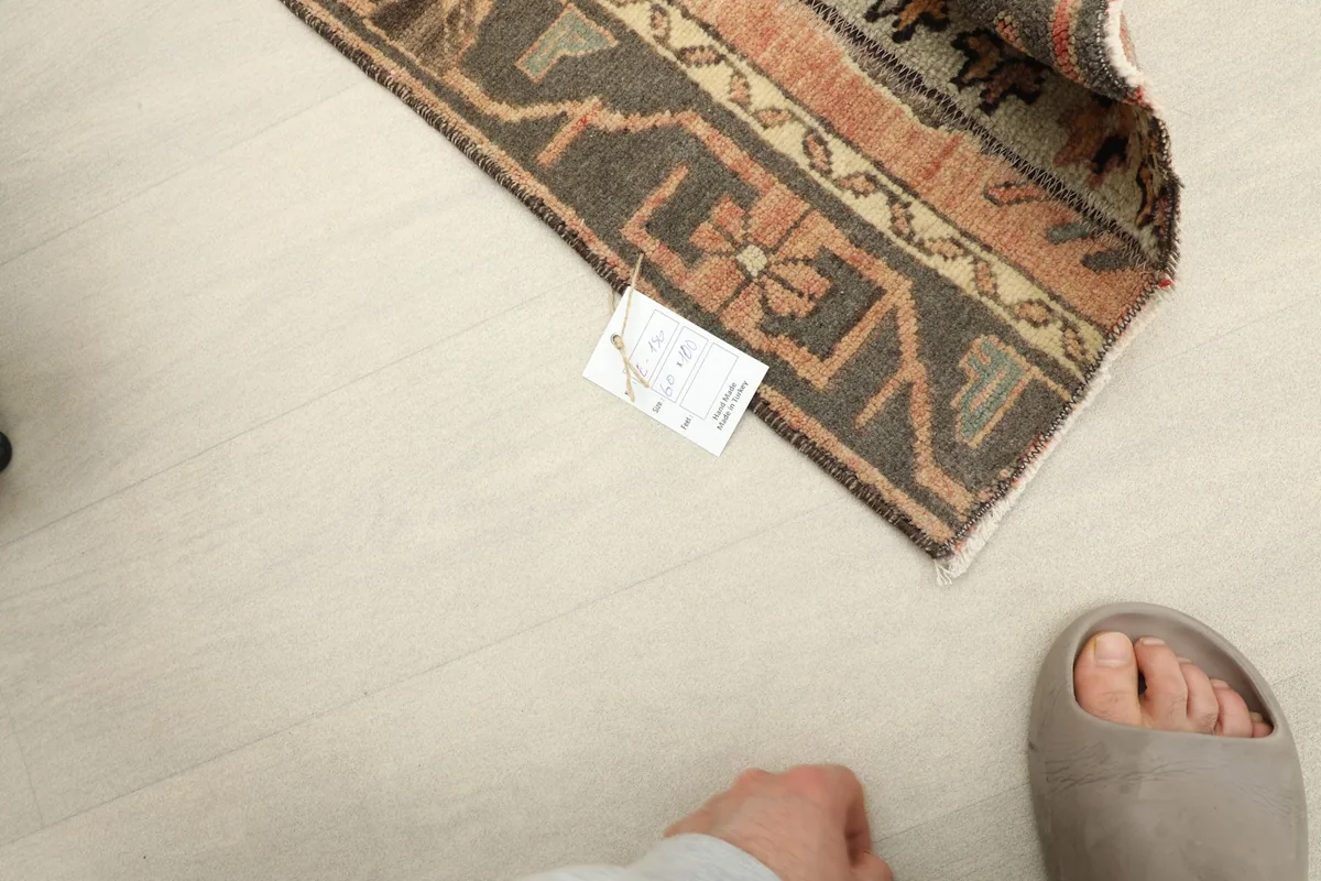 Rug laid on the floor with a foot nearby for scale, showing its size in a real-world context.