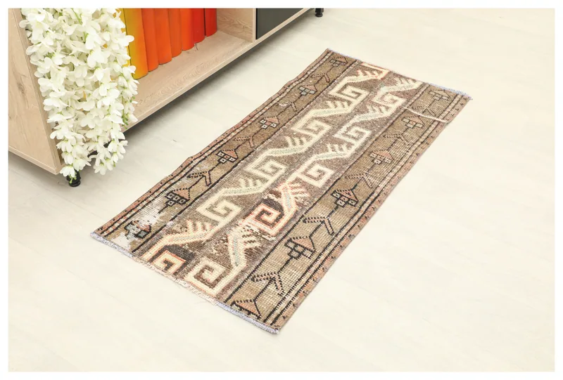 Full top view of the 1'9" x 3'9" vintage Anatolian rug with brown, tan, and ivory geometric patterns