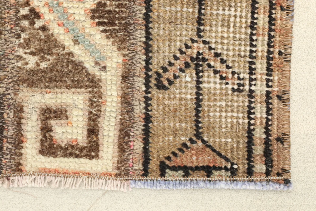 Close-up detail of the rug's fringe and a section of the brown and ivory geometric motifs