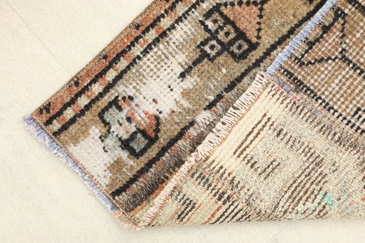 Folded corner of the rug revealing the cotton foundation and the reverse side of the hand-knotting
