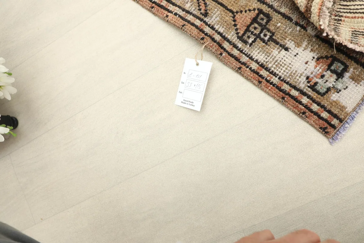 Corner of the rug with a small tag, set against a light floor, showing general scale