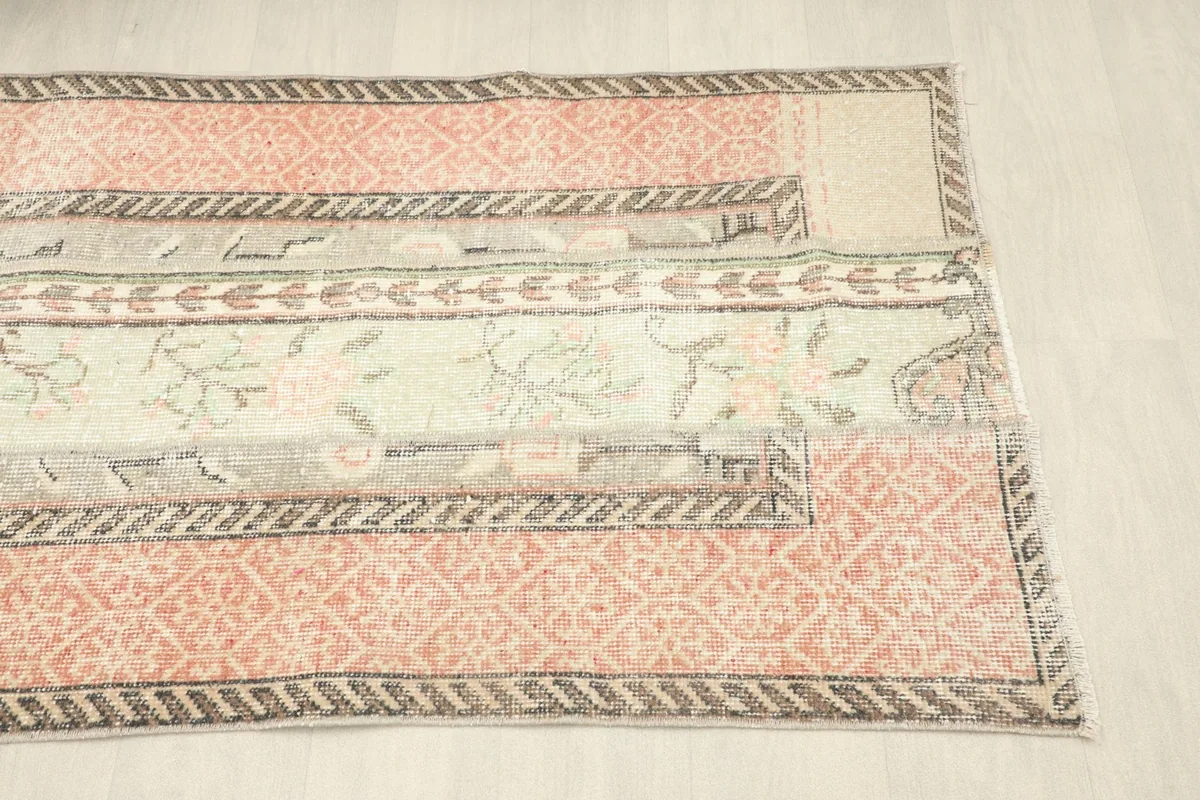 Angled view of the bottom right portion of the rug, showing the patterns and subtle color variations.