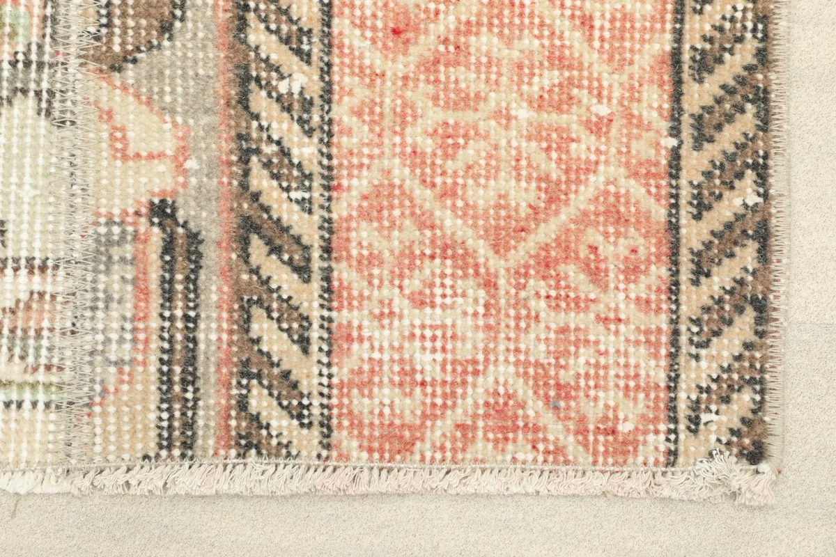 Close-up detail of the rose geometric pattern and charcoal border, showing the wool pile texture.
