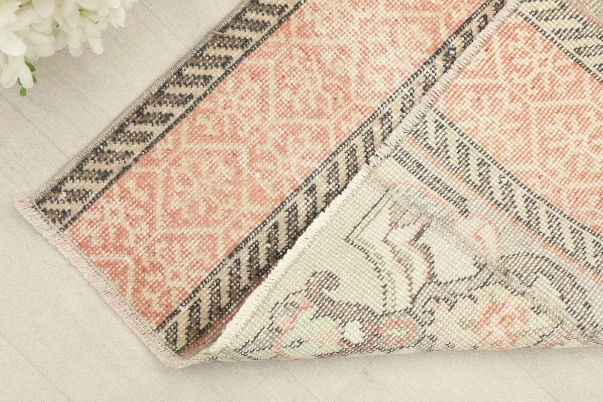 View of the rug's pile and fringe, with a corner folded back to show the cotton foundation.