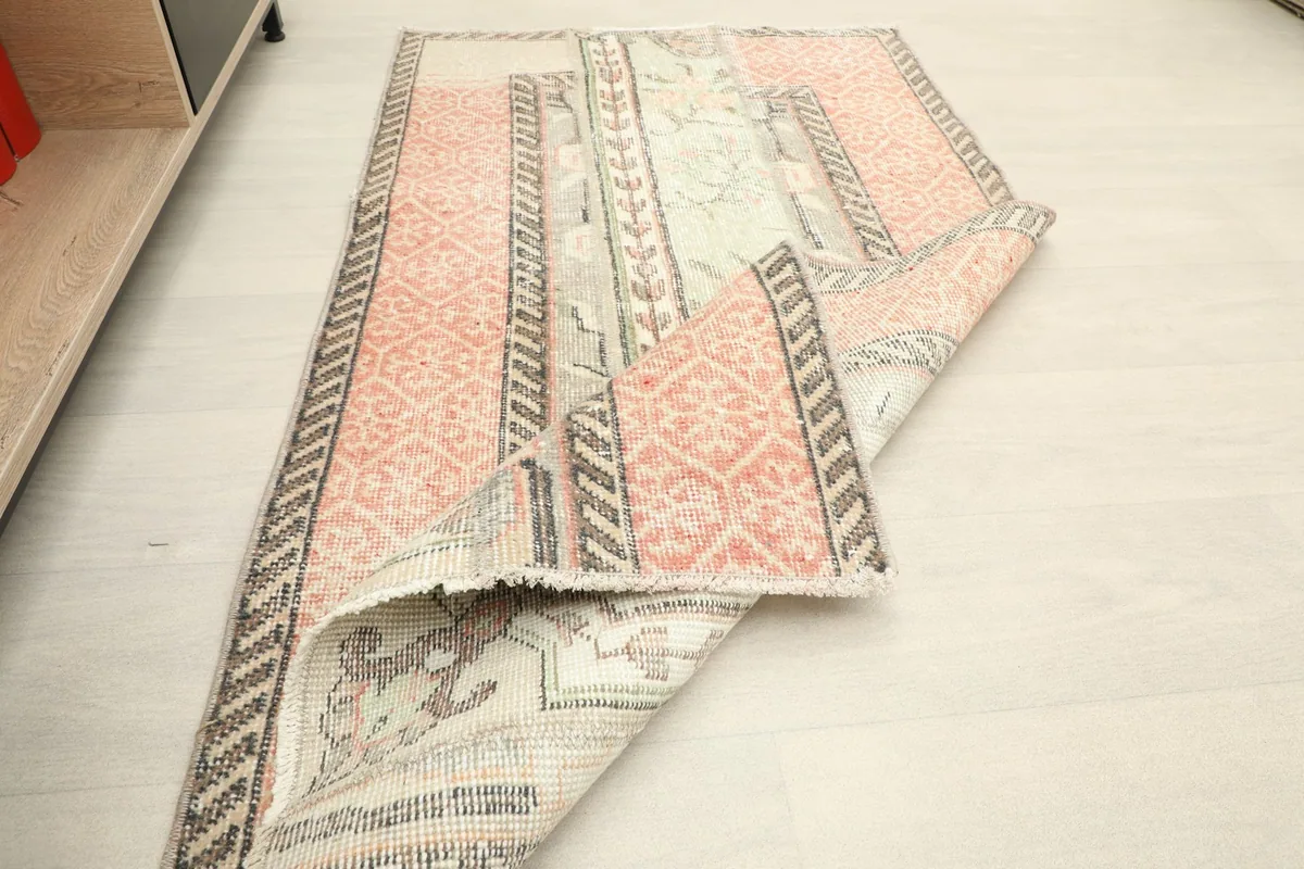 The rug partially folded, displaying the back of the hand-knotted wool on cotton foundation.