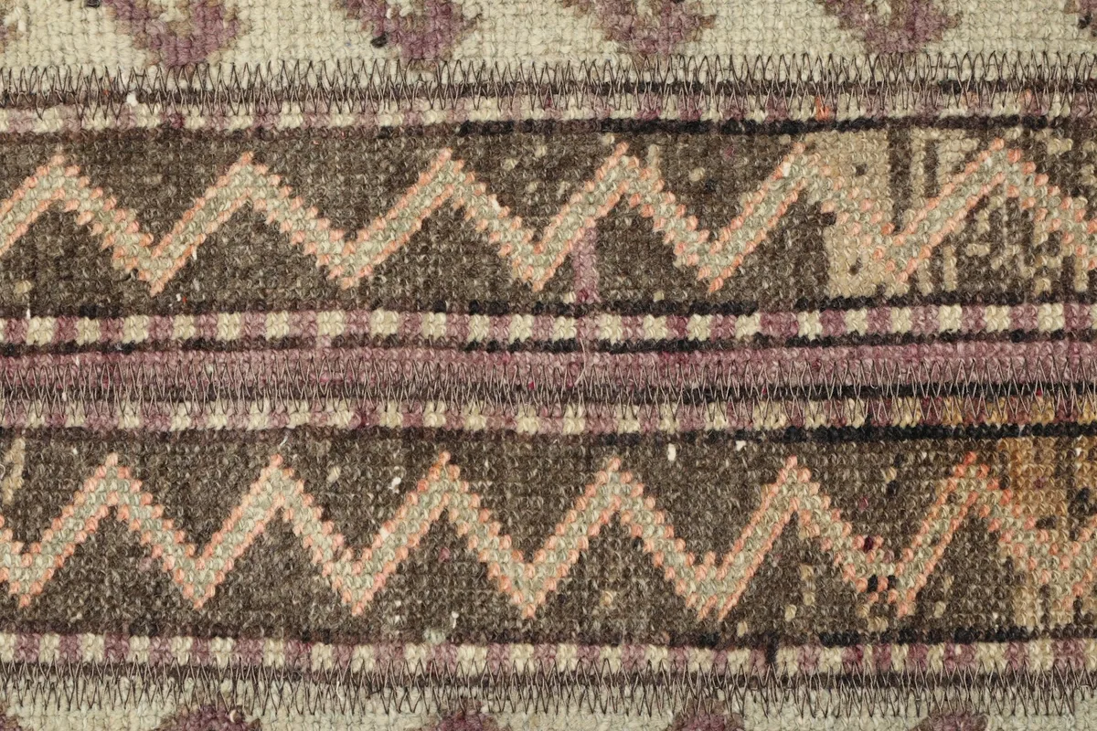 Detailed view of the central section, featuring zig-zag and striped motifs in brown and pink.
