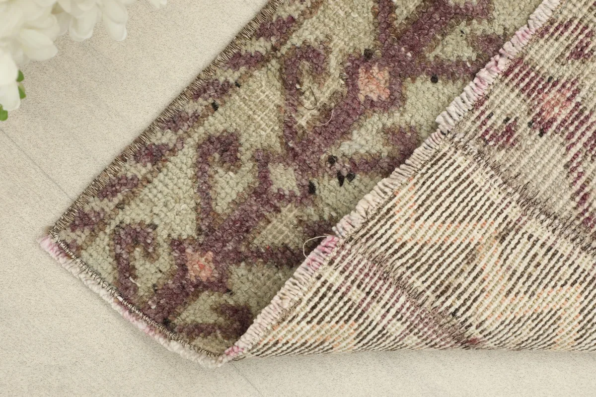Corner of the rug folded to reveal the tightly woven cotton foundation and wool pile structure.