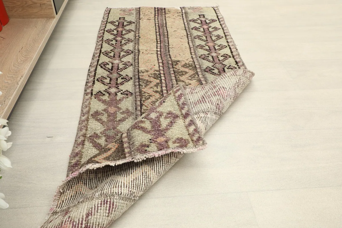 Rug partially folded, illustrating its flexibility and the vintage character of the textile.