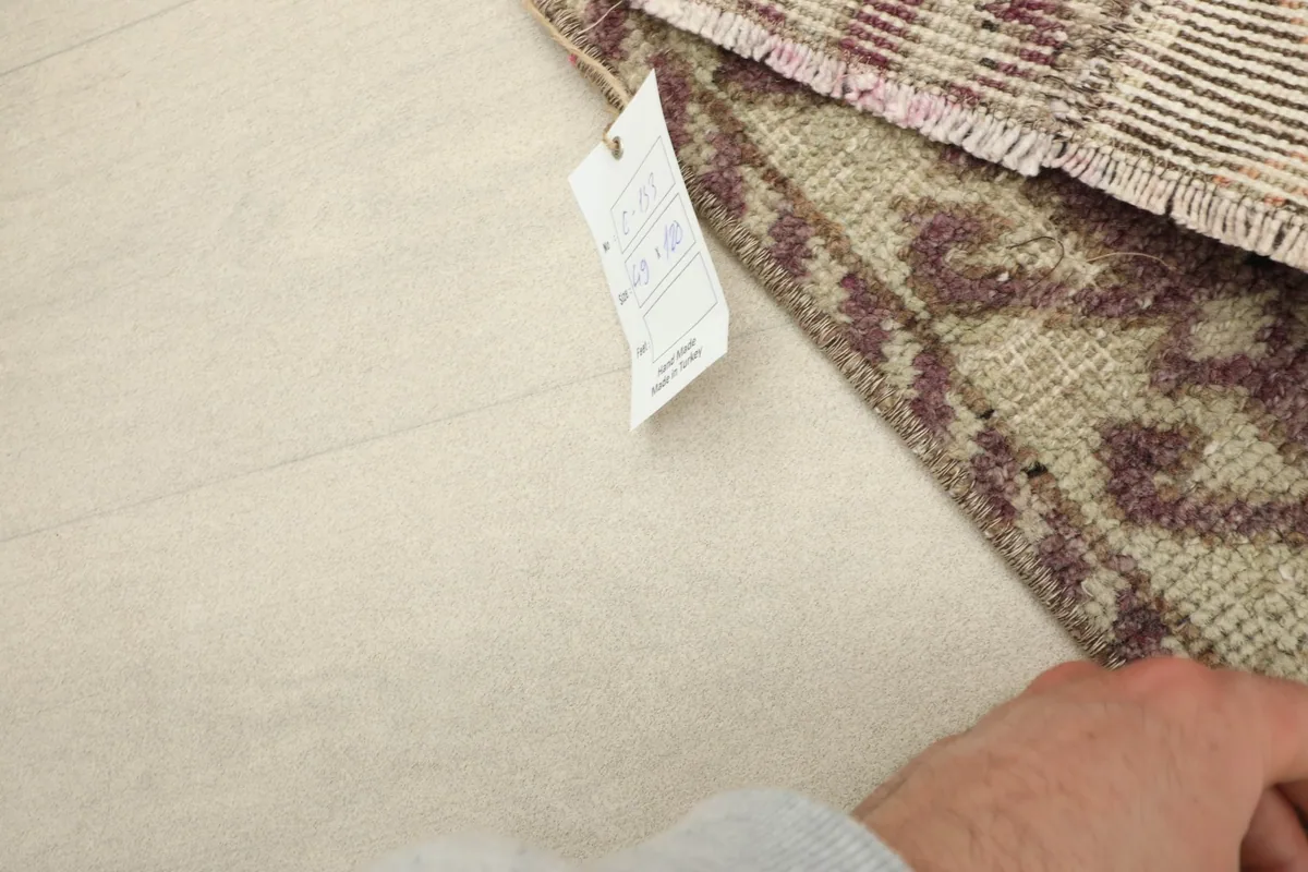 Close-up of the rug's corner with a product tag, showing the hand-knotted detail on the pile.