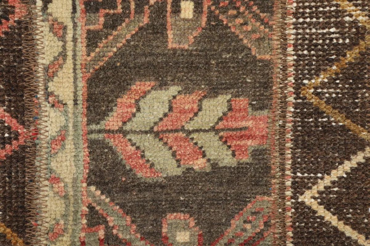 Detailed view of a tribal motif with rose and olive colors on a dark brown background