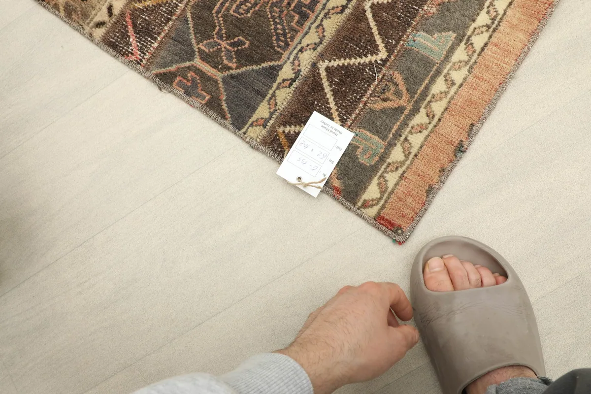 Rug next to a foot for scale, showing its mini size and tag