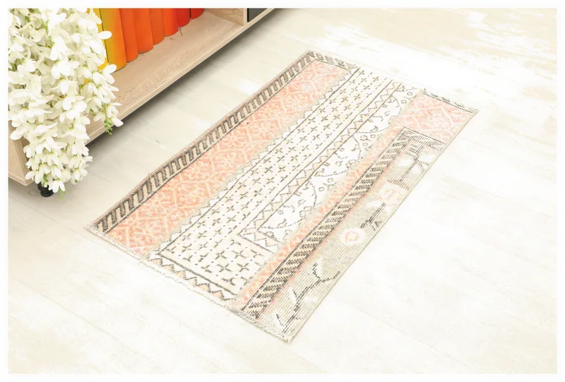 Full top view of the 1'10" x 3'1" orange and cream geometric patchwork rug on a white background.