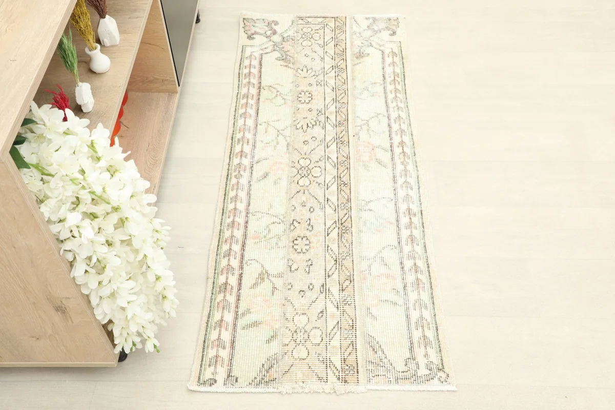 Overhead view of the vintage runner rug placed on a light floor next to a wooden console with flowers.