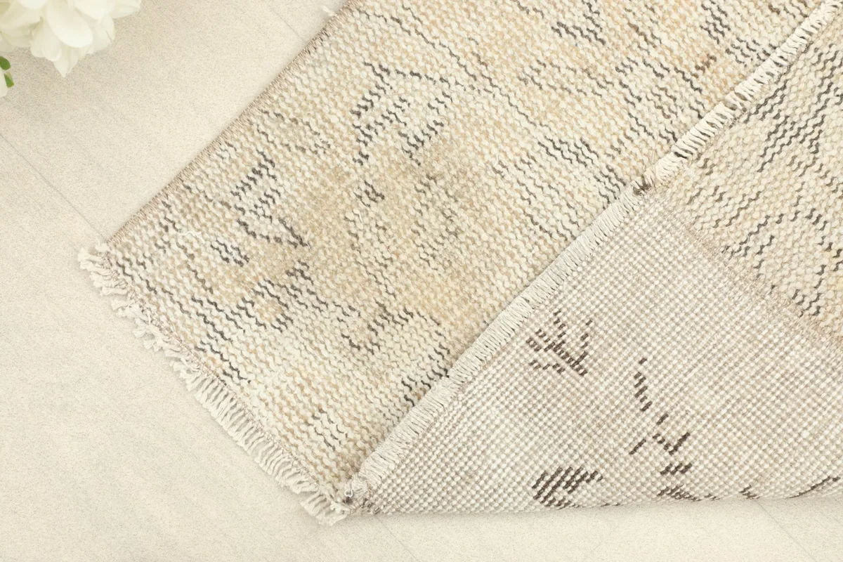 View of the rug's corner, showing the tightly woven back and the natural cotton foundation.