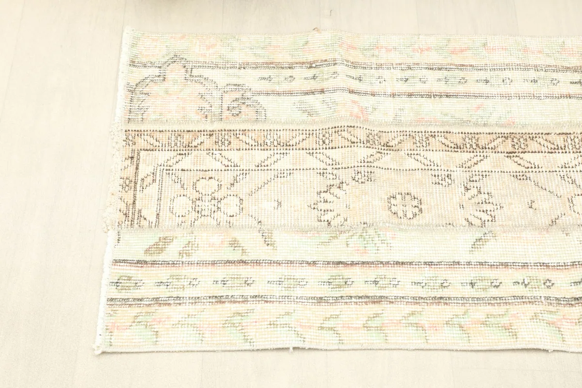 Angled shot of the rug's side, showing the linear progression of patterns and the soft color variations.