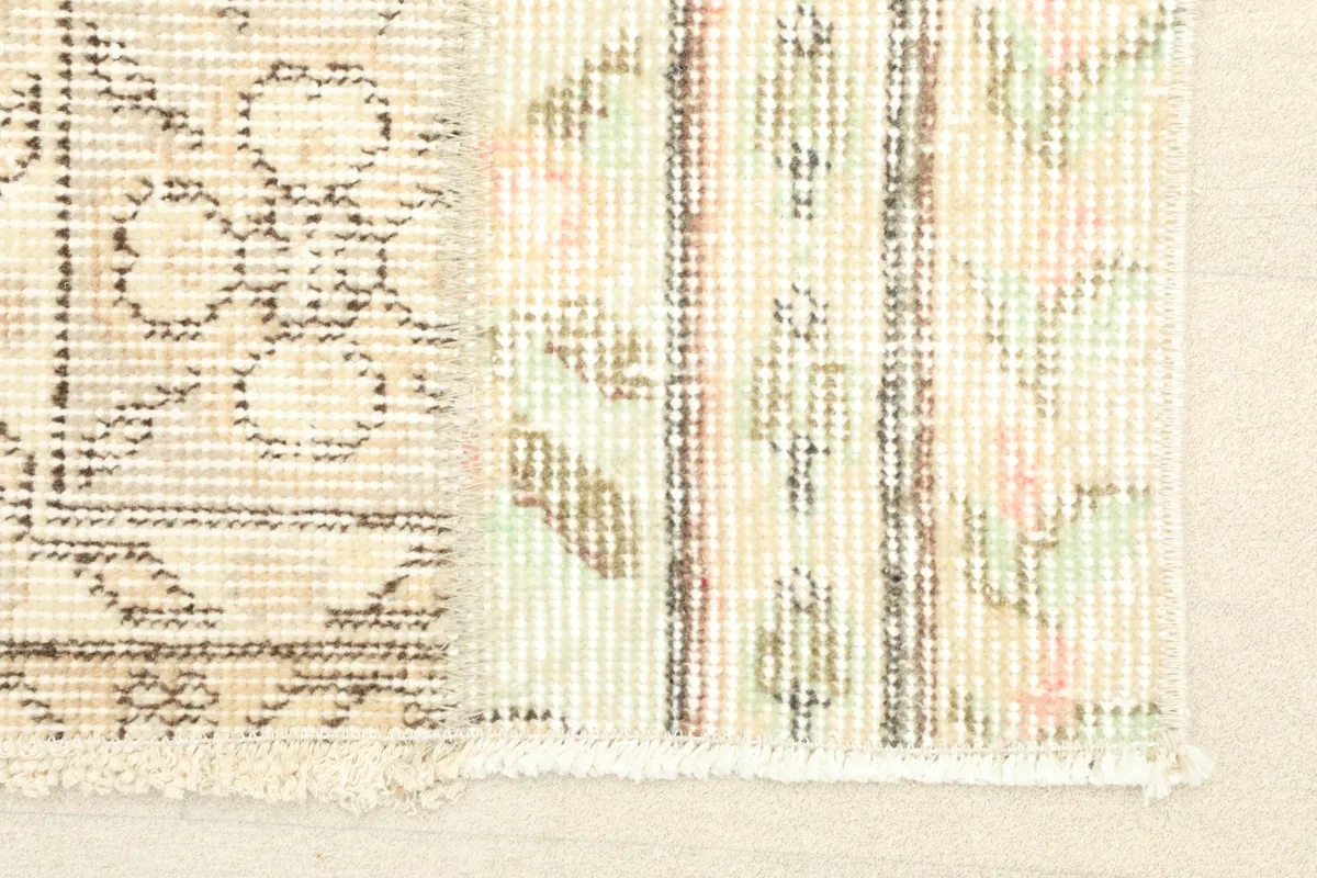 Close-up detail of the rug's surface, showing the subtle pink and green accents within the geometric patterns.