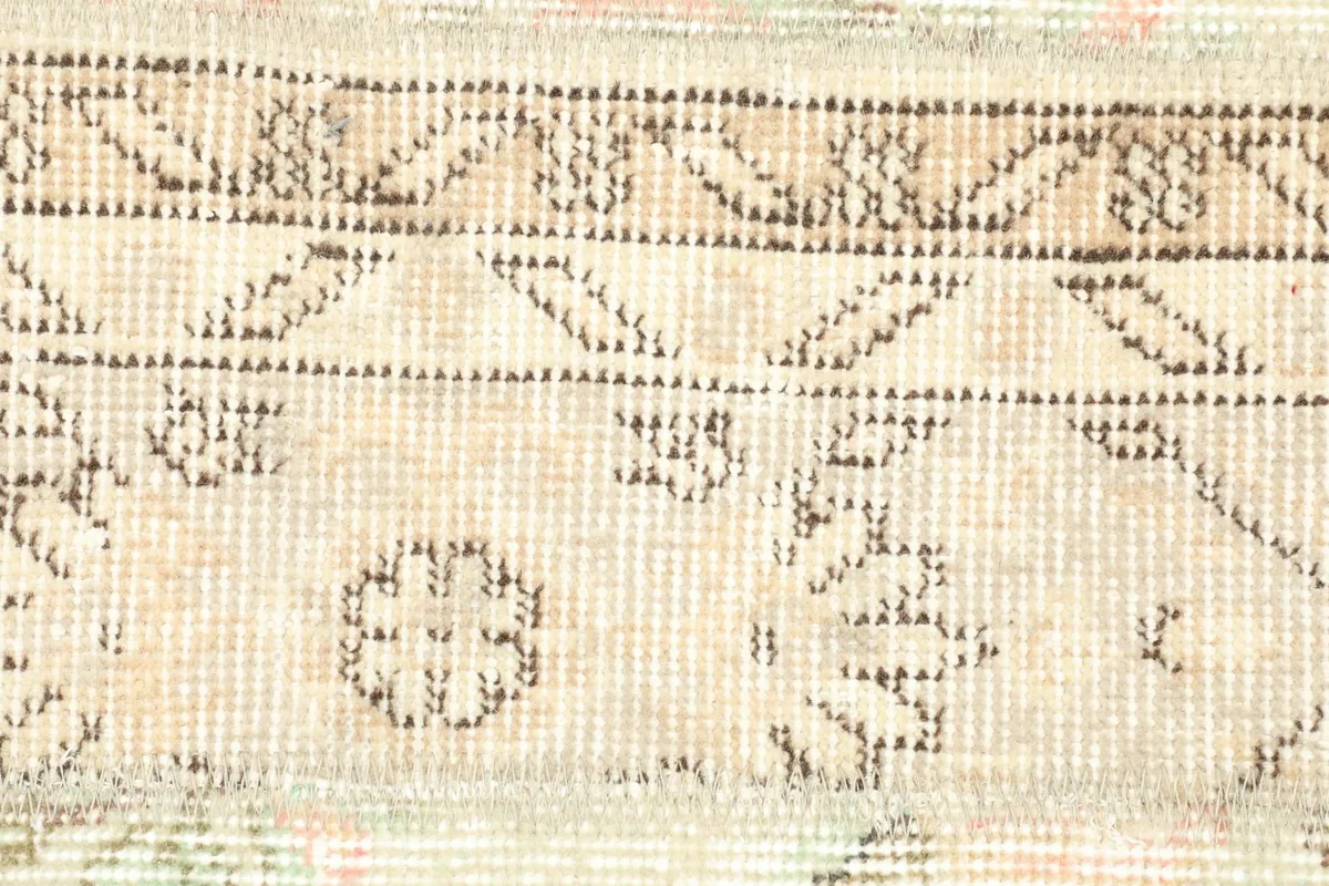 Detailed view of a section of the rug, focusing on the dark brown outlines of the geometric shapes and floral elements.