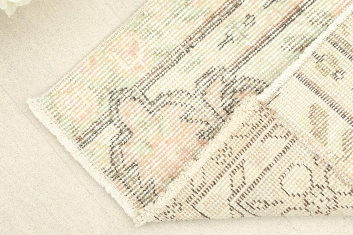 Close-up of the rug's low pile and the tight hand-knotting, with a corner folded to show the back.