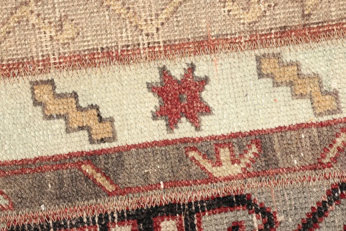 Detailed view of the wool pile showing a red star motif and tan zigzag patterns on a cream stripe