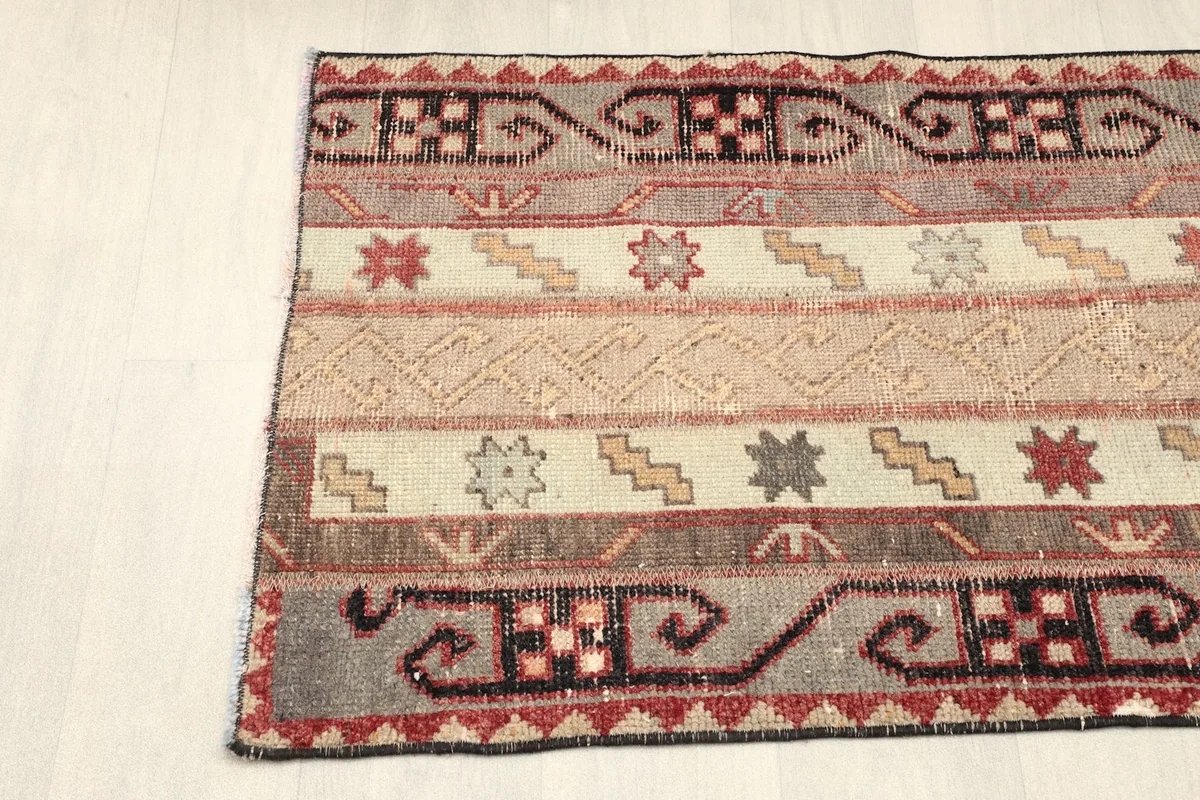 Partial view of the rug's side, focusing on the repeating geometric border design and stripe variations