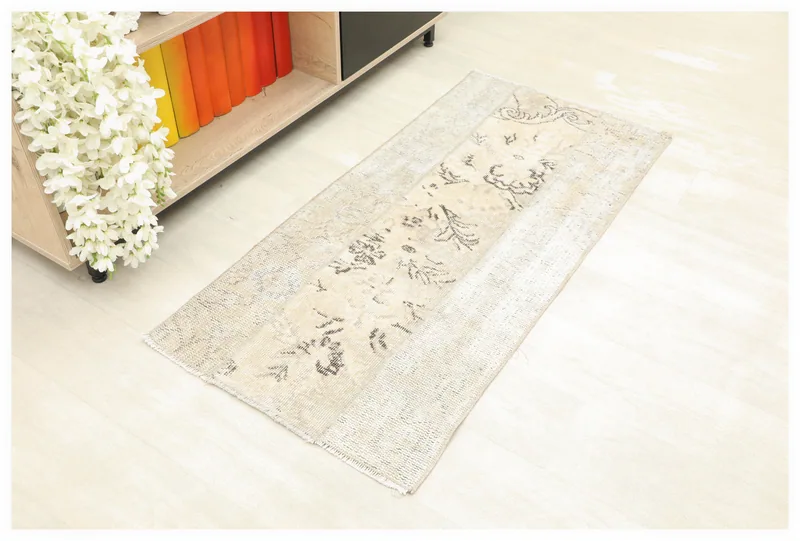 Full top view of the 2x4 beige and charcoal vintage Anatolian rug on a light floor.
