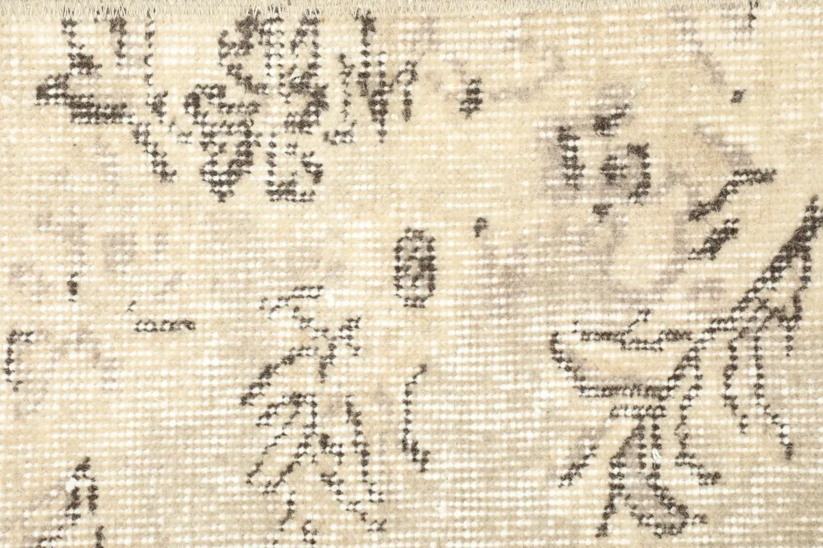 Detailed shot of the central floral motif and the low, distressed wool pile.