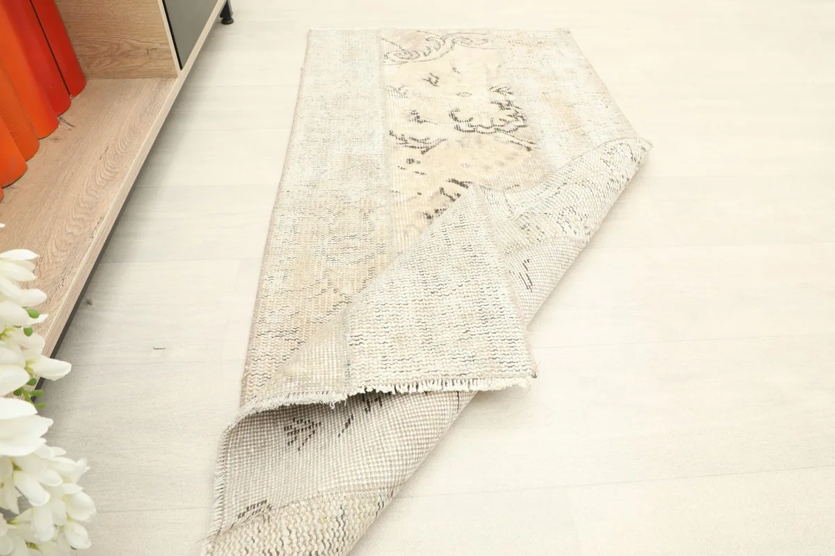 The rug partially rolled, demonstrating its flexibility and the vintage character.
