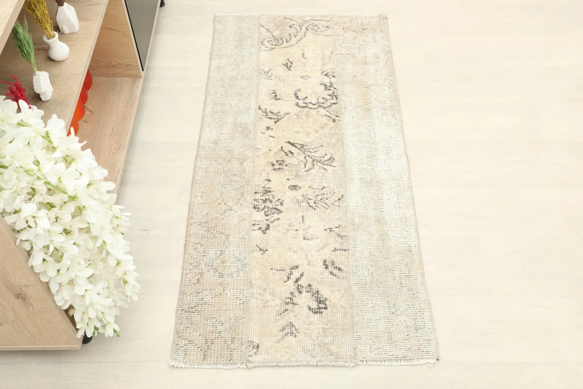 Overhead view showcasing the full length and width of the distressed beige wool rug.
