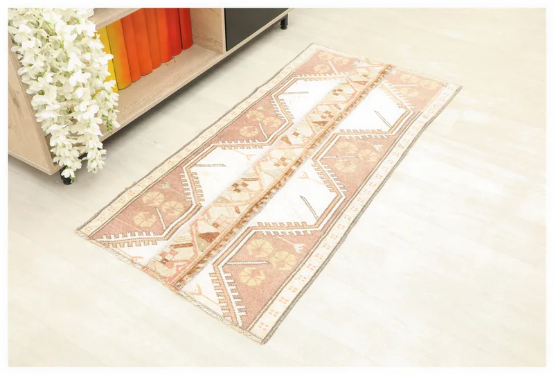 Top view of a 2'1" x 4'5" vintage Anatolian rug with rose and beige geometric patterns.
