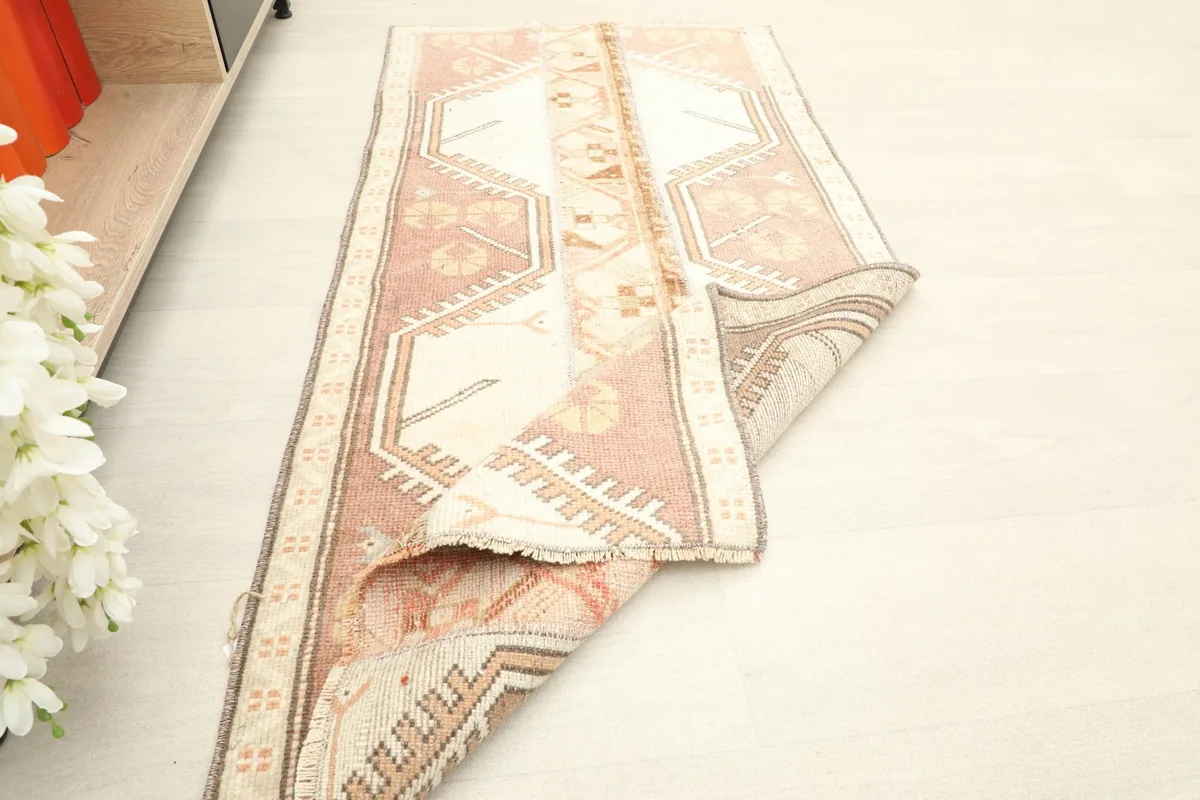 Rug partially rolled, placed next to a shelf with books, demonstrating its size and home decor potential.