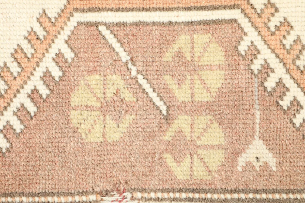 Extreme close-up of the low wool pile, revealing the texture and hand-knotted details of the rose and yellow motifs.