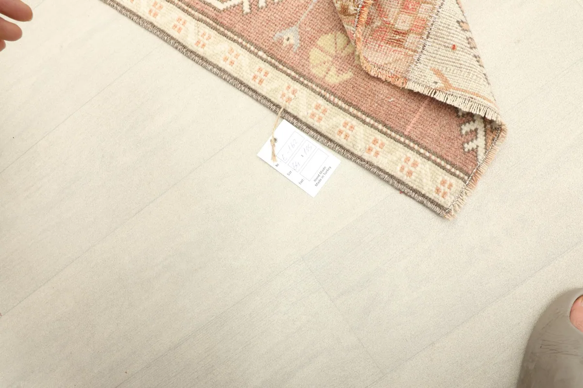 Close-up of the back of the rug, showing the tight knotting and tag, with a foot for scale.